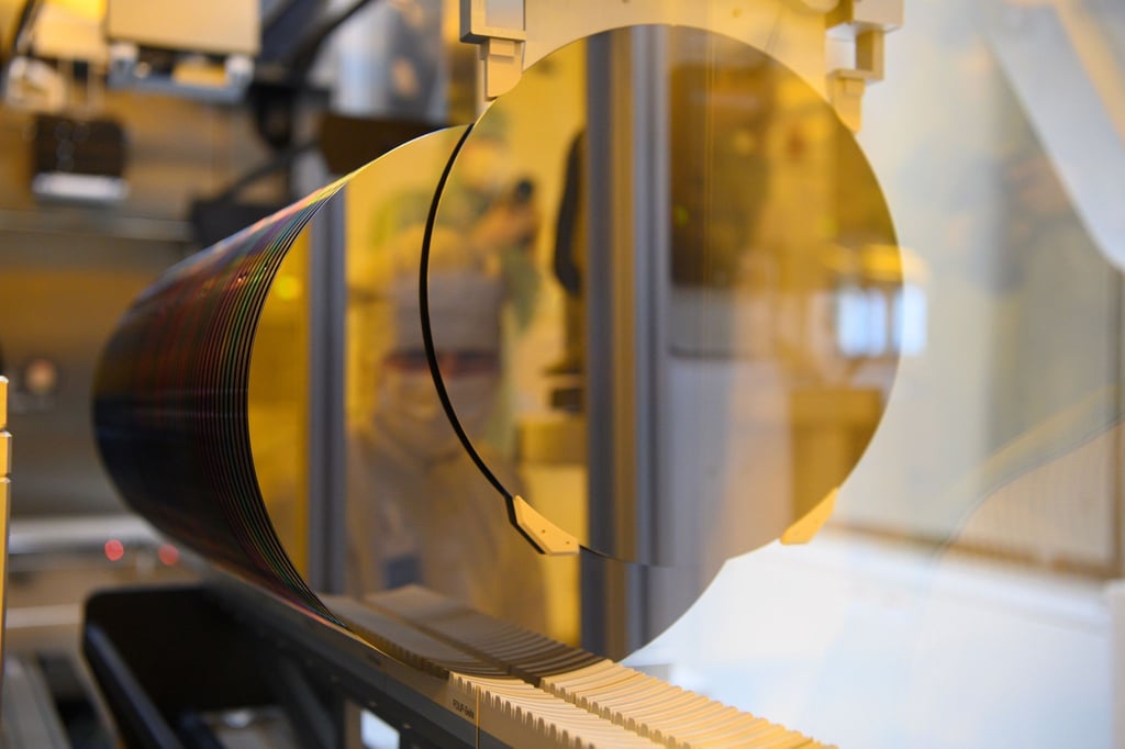 Ein Mitarbeiter spiegelt sich während eines Presserundgangs in der neuen Halbleiterfabrik von Bosch im Reinraum in einem 300-Millimeter-Wafer.