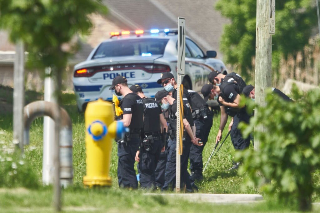 Polizisten in Reihe untersuchen den Tatort eines Autounfalls in London, Ontario. Nach einem Angriff mit einem Auto, bei dem vier Menschen aus einer muslimischen Familie getötet worden sind, geht die Polizei Berichten zufolge von einem rassistischen Tatmotiv aus.