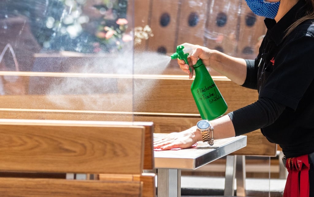 Eine Mitarbeiterin eines Restaurants reinigt einen Tisch.