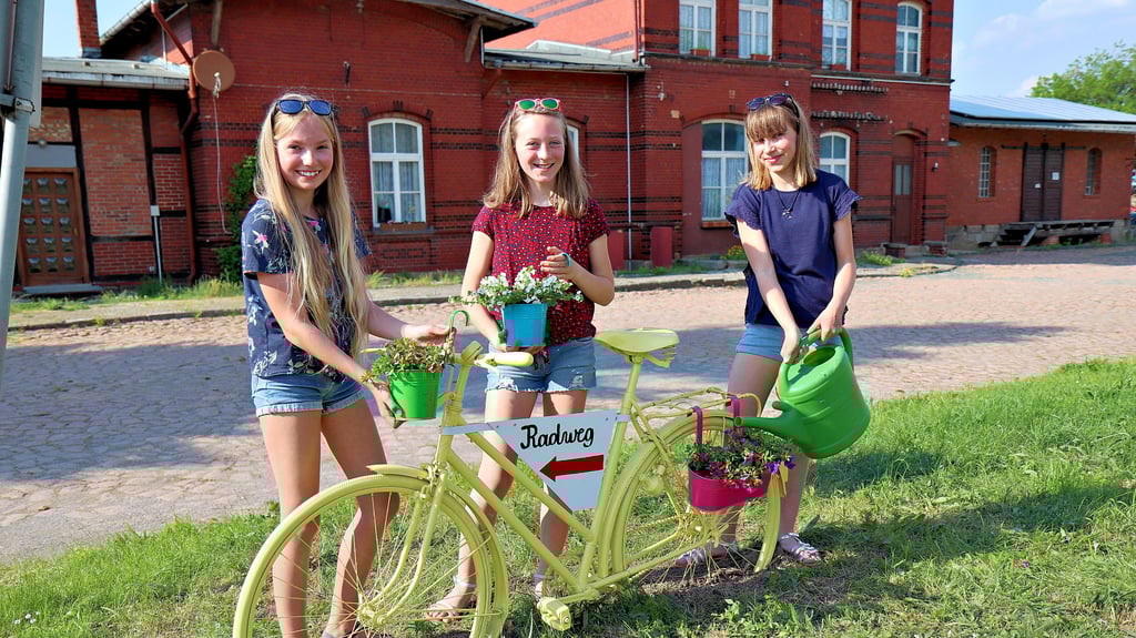 Teresa Korn, Finja Blume und Luise Mauritz (von links) bepflanzen das Rad, das an der Dingelstedter Bahnchaussee auf den Huy-Radweg verweist.