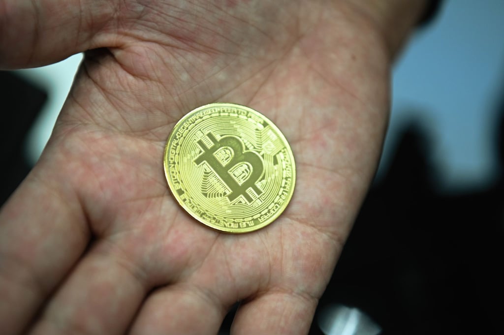 Ein Mann mit eine nachgemachter Münze mit dem Bitcoin-Logo.