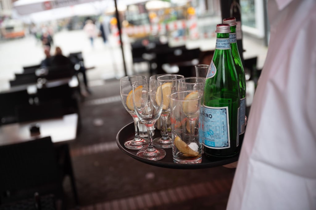 Ein Kellner räumt in einem Restaurant einen Tisch ab.