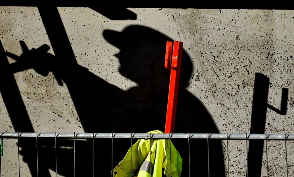 Ein Arbeiter ist auf einer Baustelle beschäftigt und wirft dabei einen dunklen Schatten.
