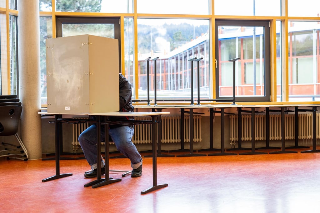 Ein Wähler sitzt in einem Wahllokal.