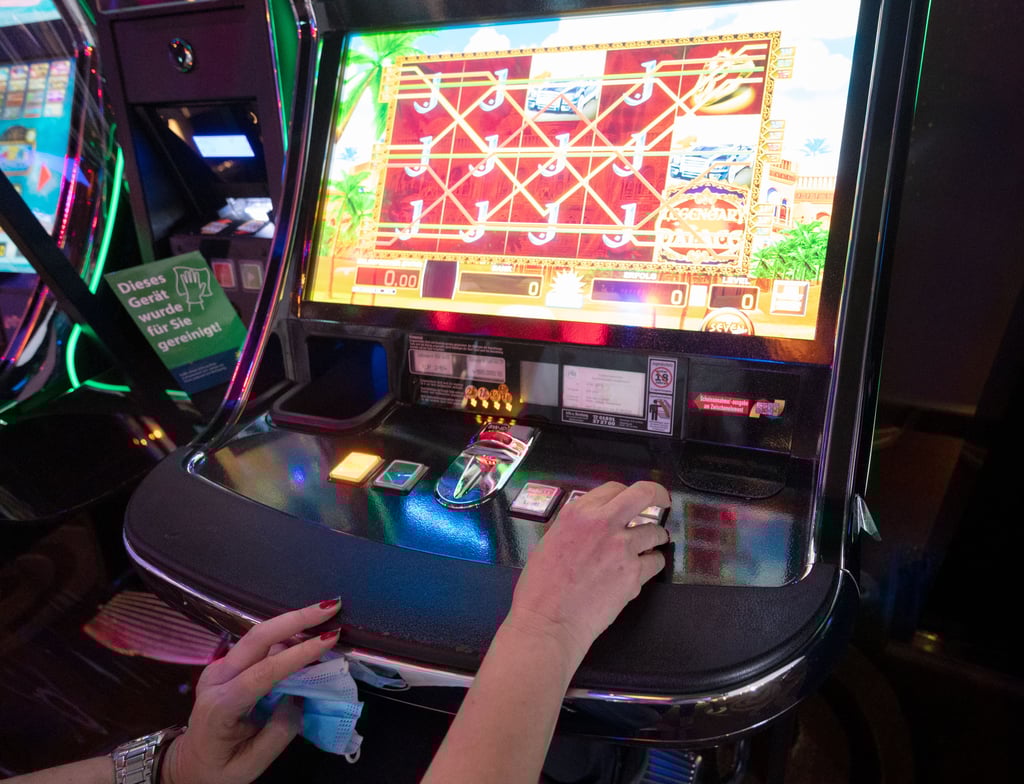 Eine Frau sitzt in einer Spielhalle vor einem Spielautomaten.