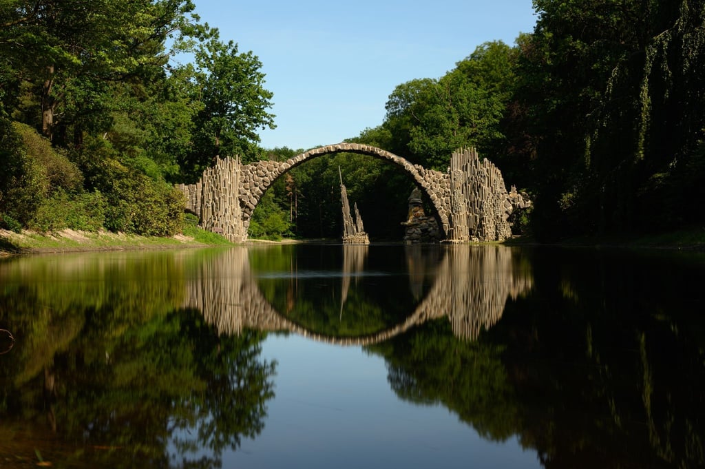 Die Rakotzbrücke bildet einen steinernen Kreis mit dem Wasser im See des Azaleen- und Rhododendren-Parks in Kromlau im Landkreis Görlitz.