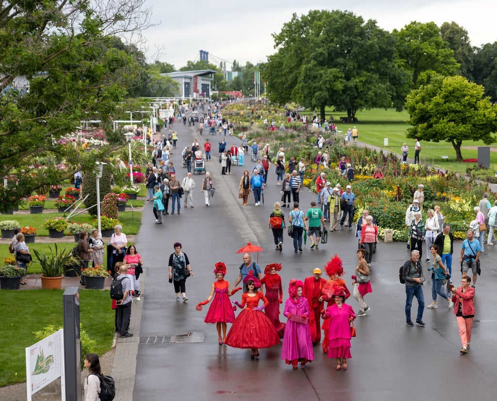 Menschen in roten Kostümen nehmen an einem sogennanten „Walking Act“ teil und gehen über das Gelände der Bundesgartenschau im Egapark auf der Buga.