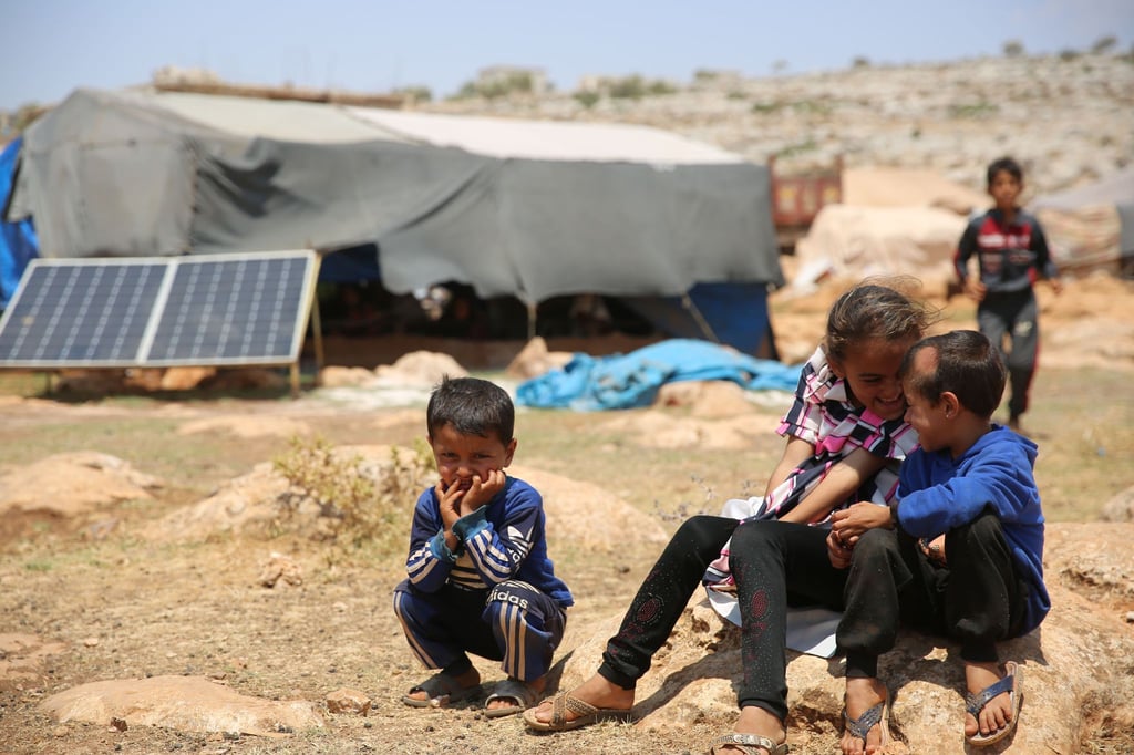 Geflüchtete Kinder sitzen in einem Flüchtlingslager nordwestlich von Aleppo auf einem Stein.