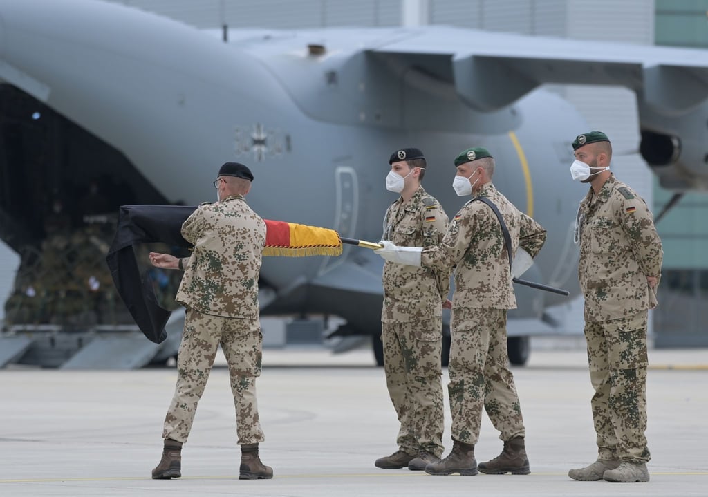 Brigadegeneral Ansgar Meyer (l), der letzte Befehlshaber der Bundeswehr in Afghanistan, rollt vor dem Transportflugzeug vom Typ Airbus A400M der Luftwaffe die Truppenfahne ein.