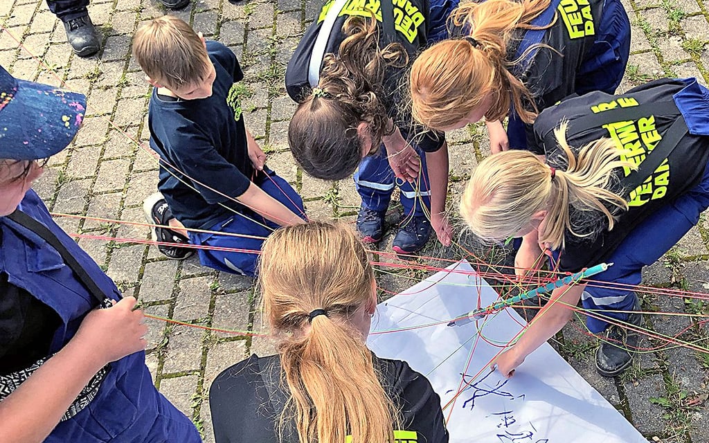 Ganz schön knifflig: Das Team der Dankeröder Jugendfeuerwehr versucht, den großen Stift mit dem an ihm befestigten Bändern zu bewegen - und so auf dem Papier zu schreiben.