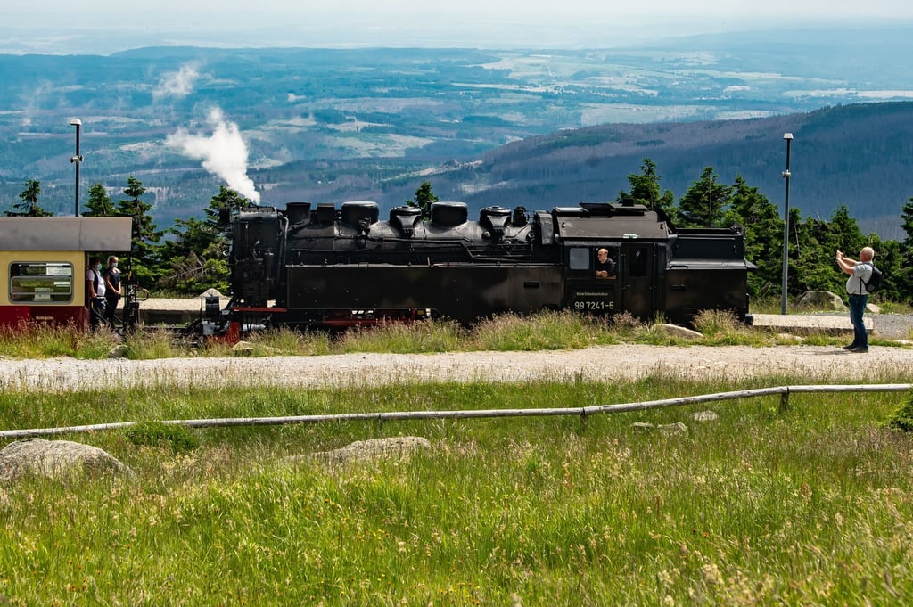 Ein Wanderer fotografiert die dampfende Brockenbahn.
