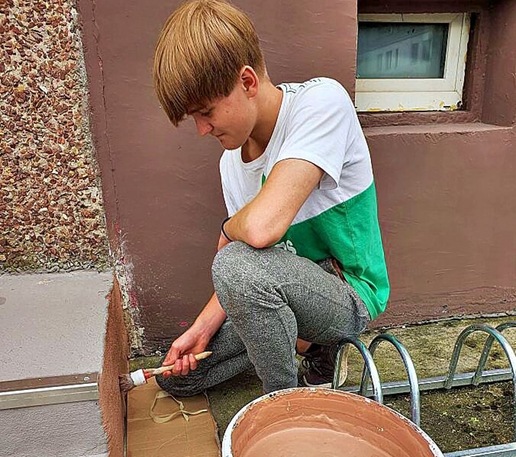 Keven Winkelmann streicht im Oberfelder Weg eine Treppe.