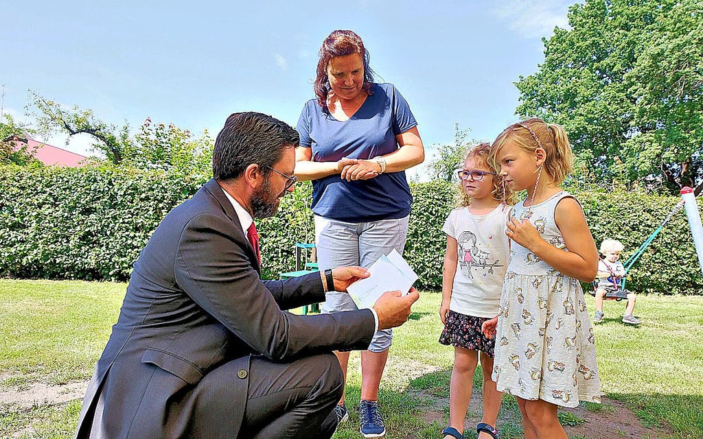 Emma Stets (rechts) und Anna Schneider überreichen Björn Kieselstein von der Sparkasse Wittenberg zwei selbstgemalte Bilder.