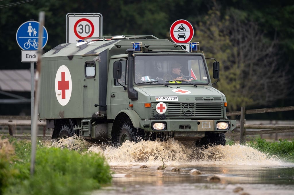 Ein Sanitätsfahrzeug der Bundeswehr fährt über eine überflutete Straße.