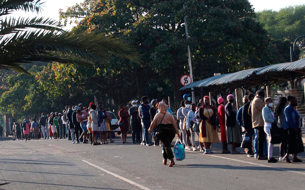 Menschen stehen in Durban vor einem Einkaufszentrum Schlange, um sich mit dem Nötigsten zu versorgen.