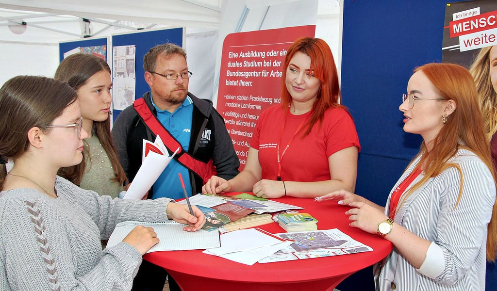 Saskia (von links) und Fabienne Tarja Kreiser informieren sich mit ihrem Vater am Stand der Agentur für Arbeit bei Carina Koppers und Maria Zschorn über die Ausbildungsmöglichkeiten.