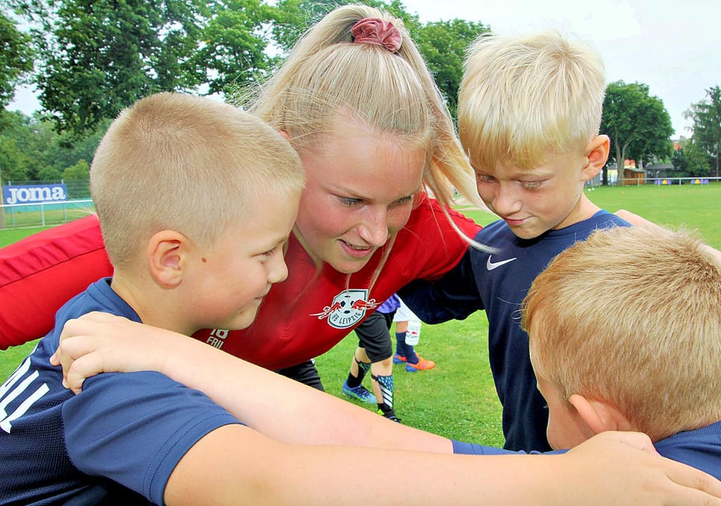 Lena Zimmermann von der Fußballschule von RB Leipzig schwört die Jungs Finn, Jonah und Erik aufs Training ein.