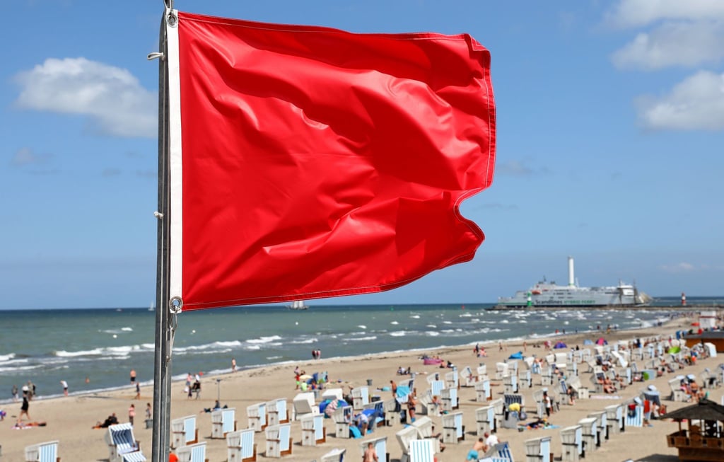 Am Ostseestrand signalisiert eine rote Flagge am Turm der Wasserwacht des DRK "Baden und schwimmen verboten".