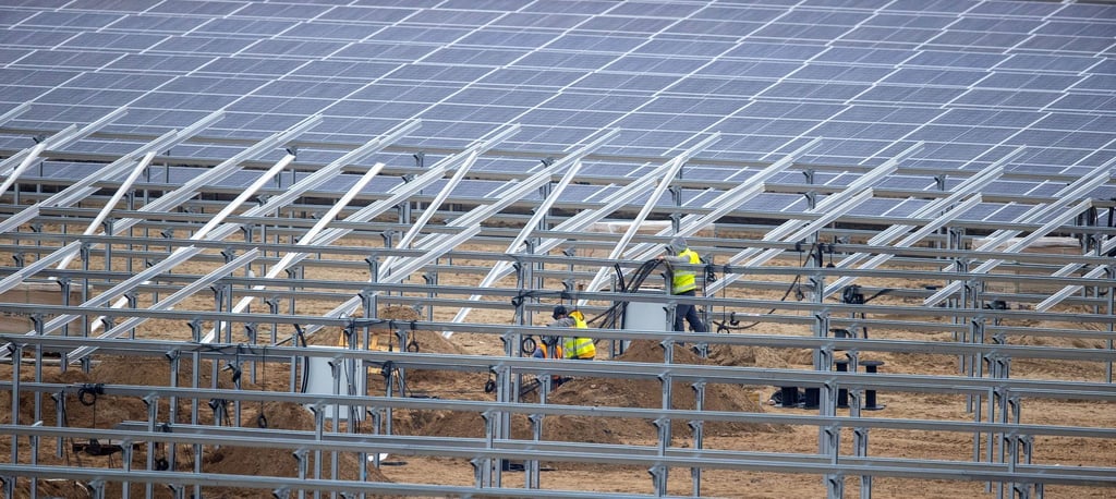 In einem ehemaligen Kiestagebau in Mecklenburg-Vorpommern errichten Installateure einen Solarpark.