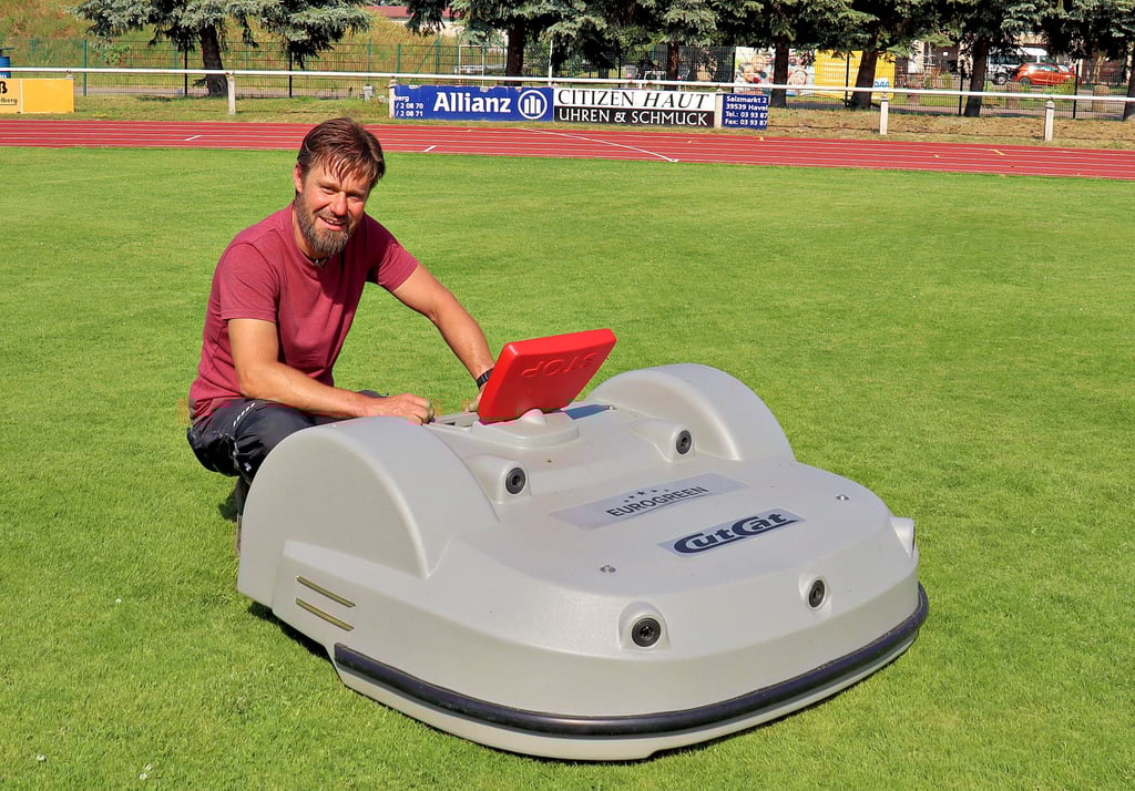 Stadtelektriker Ralf Westphal mit dem Miniroboter auf dem Fußballplatz des Havelberger Sportforums. Er kennt sich bestens aus mit der Programmierung des Gerätes.