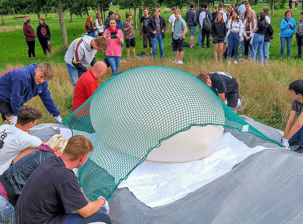 Mit einem Netz fixiert die Gruppe den Ballon, während er aufgepumpt wird.