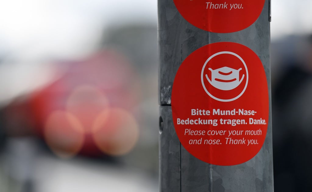 „Bitte Mund-Nase-Bedeckung tragen“ steht auf einem Aufkleber.