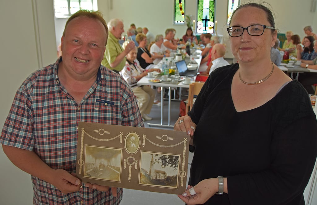 Pfarrerin Rabea M. Reinhold und Norbert Sierig, Vorsitzender des Gemeindekirchenrates Rätzlingen, zeigen historische Fotos von der Kirche und von Max Ebeling, dem Namensgeber des neuen Gemeinde- und Kulturzentrums in Rätzlingen.