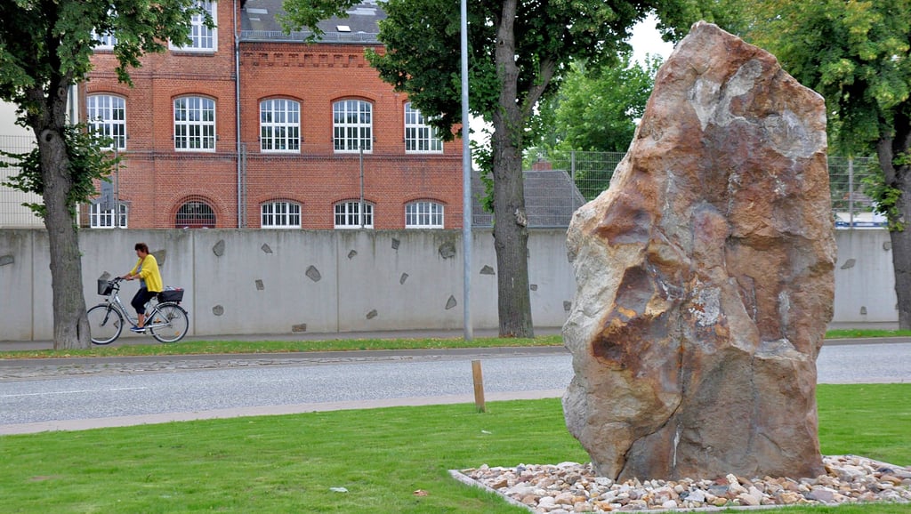 Der gerade wiedererrichtete Guddenstein wird Namensgeber für die Grundschule Güsten. Das Gebäude im Hintergrund gehört übrigens zur Freien Sekundarschule Güsten. Wie Sabine Rotter informierte, hatte den Namen bereits die Schulkonferenz 2016 beschlossen. Die neue bestätigte nun den Namen ?Grundschule am Guddenstein?. Momentan stehe der Umzugstermin 12. und 13. August vom Provisorium zurück in die sanierte Grundschule. Man hoffe, dass die neuen Möbel bis zum neuen Schuljahr ebenfalls noch kommen.