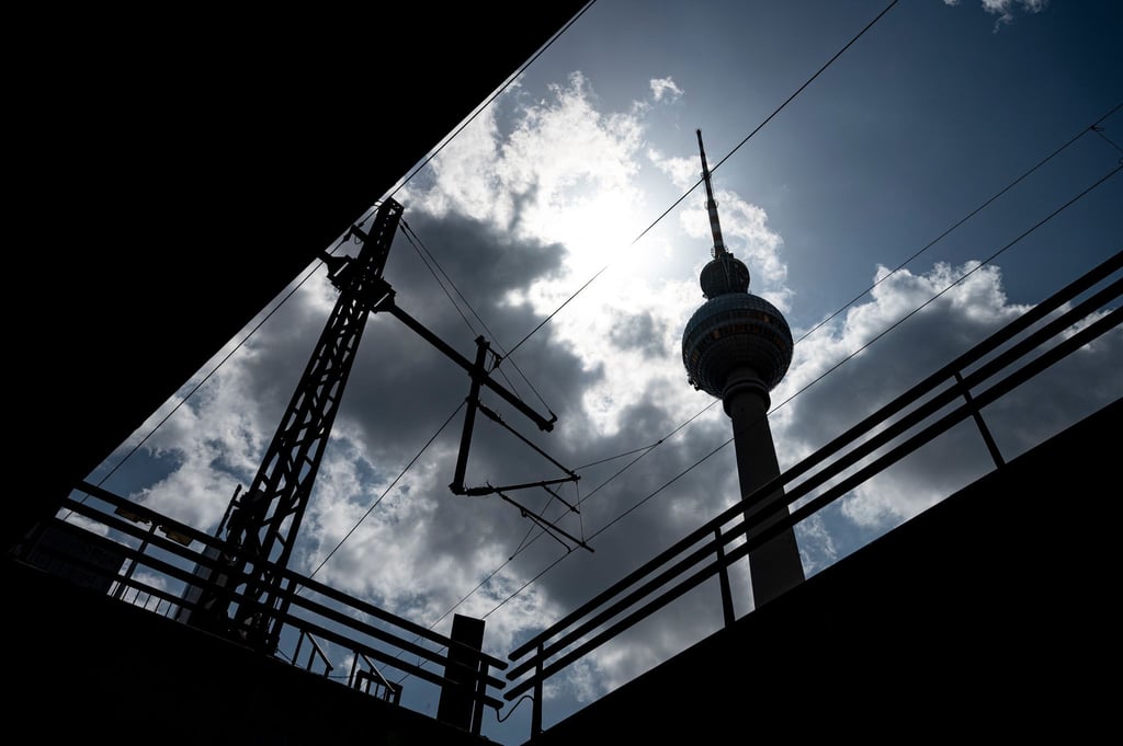 Die Sonne scheint hinter dem Fernsehturm durch die Wolken.