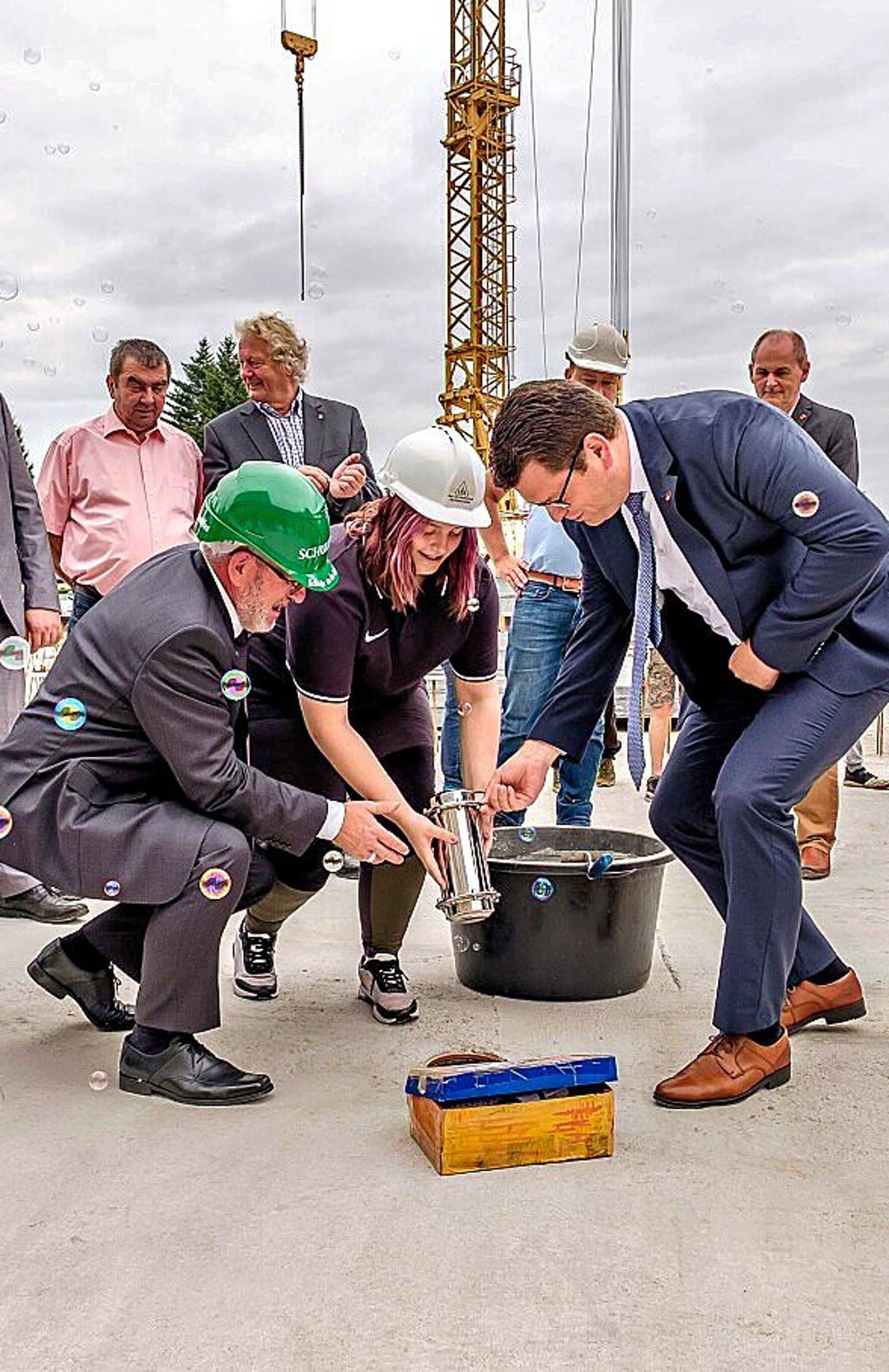 Die Zeitkapsel mit den Dokumenten wird eingelassen. Die der Kinder folgt.