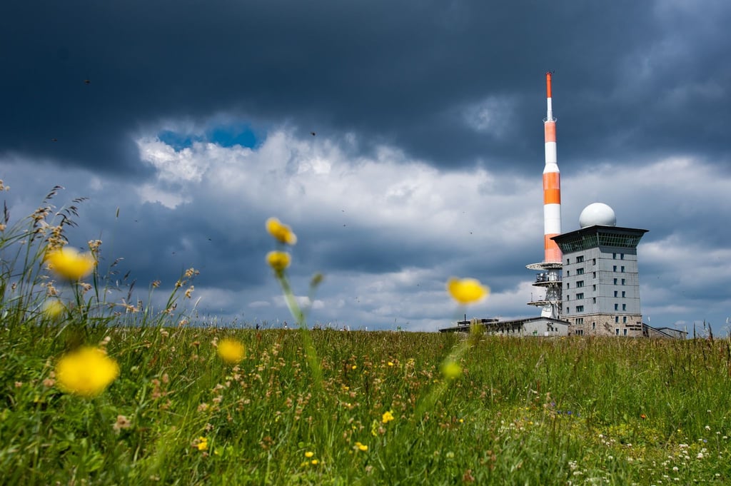 Dunkle Wolken ziehen über die Brockenherberge mit Funkturm auf dem Brocken im Harz.