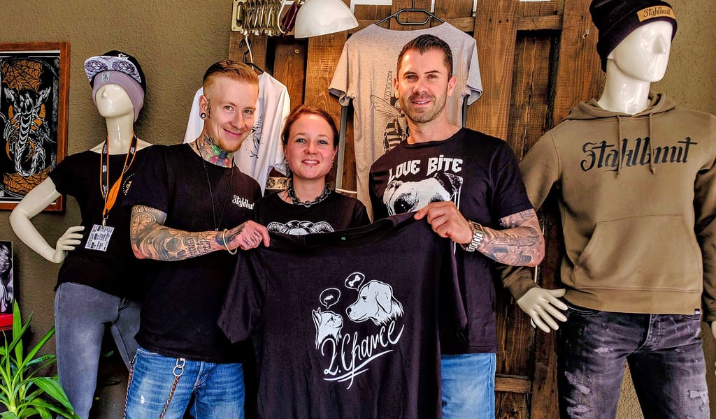 Dennis Fräßdorf, Inhaber von „Kunst und Leidenschaft“, Freundin und Kollegin Anna Wolter und „Stahlbunt“-Unterstützer Dominik Kallenbach präsentieren die Charity-Kollektion der Bekleidungsmarke.