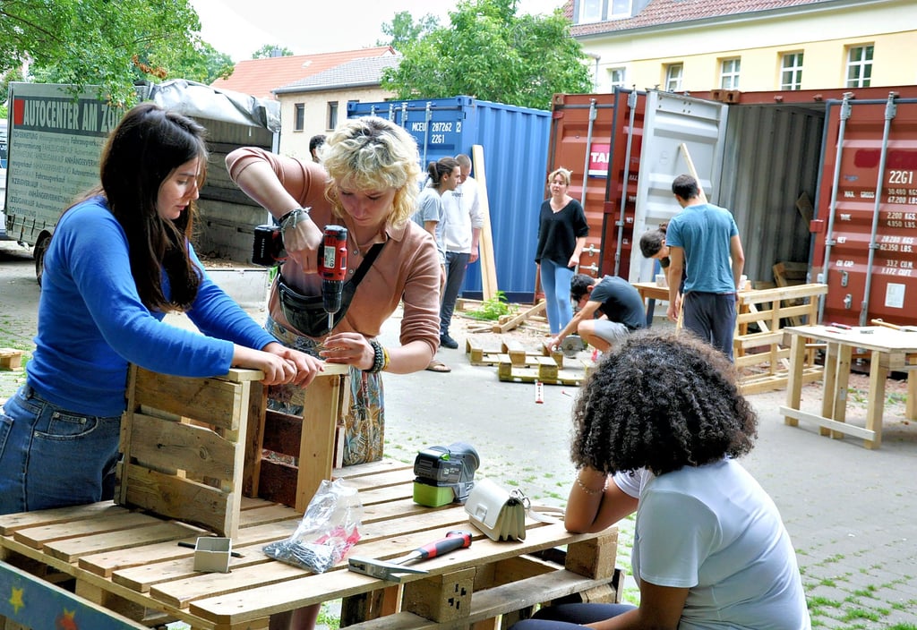 Internationale Helfer bauen unter anderem Tische und Bänke für die Kinderstadt aus Europaletten.