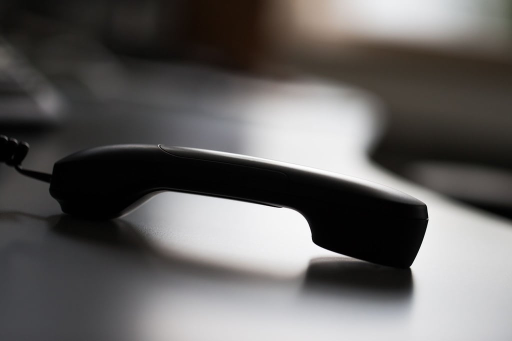 Ein Telefonhörer liegt auf einem Tisch.