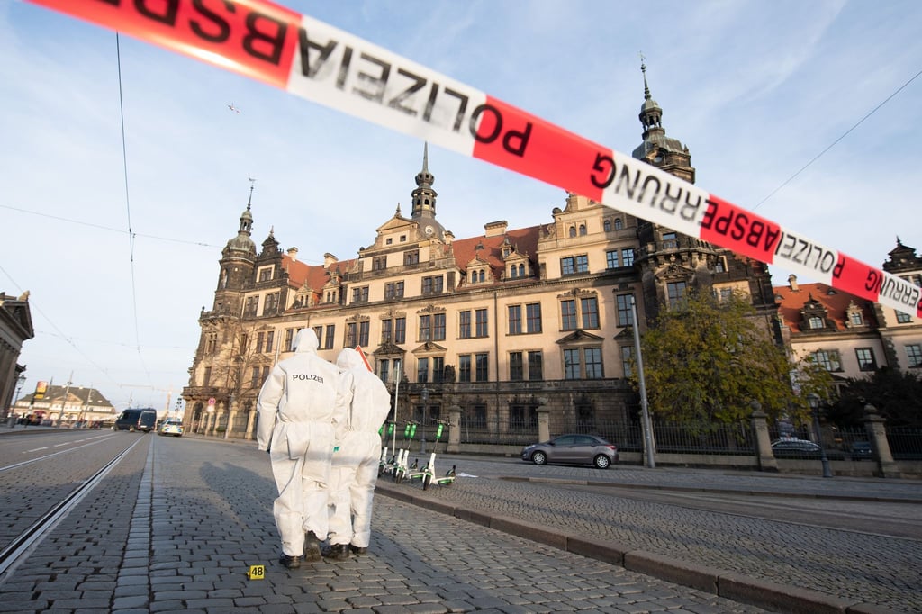 Zwei Mitarbeiter der Spurensicherung stehen vor dem Residenzschloss mit dem Grünen Gewölbe hinter einem Absperrband.