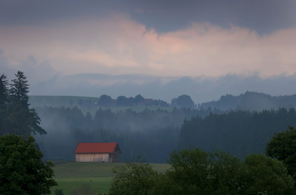 Eine Holzhütte steht im Abendlicht in der wolkenverhangenen Allgäuer Landschaft bei Marktoberdorf. (Archivbild)
