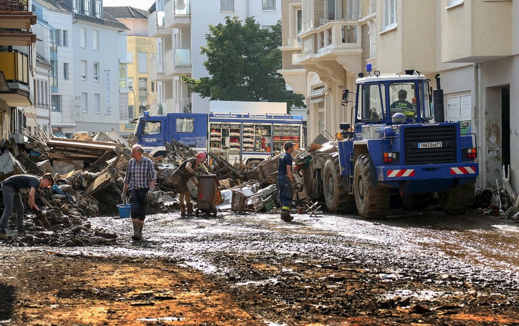 Mitarbeiter des Technischen Hilfswerks (THW) helfen bei Aufräumarbeiten nach der Unwetterkatastrophe in einer verschlammten Straße.