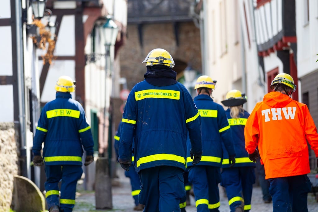 Mitglieder des Technischen Hilfswerks (THW) gehen bei Räumarbeiten nach der Unwetter-Katastrophe in Nordrhein-Westfalen durch einen zerstörten Ort.