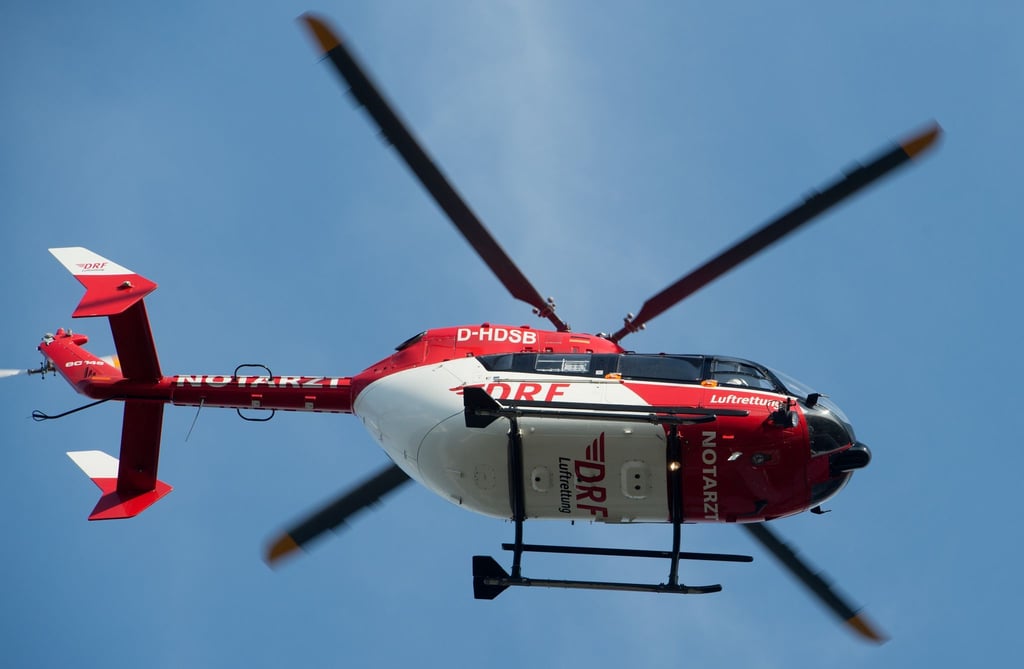 Ein Rettungshubschrauber fliegt über einen Flugplatz.