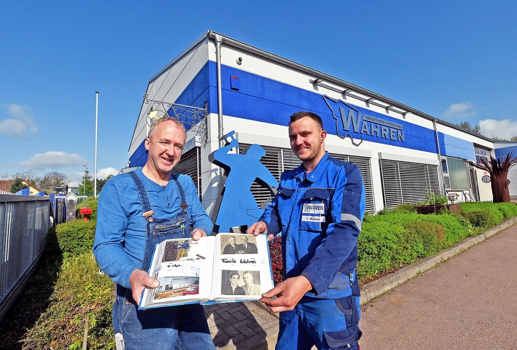 Andreas Wahren und Sohn Florian (v. li.) haben vor dem Firmensitz in Langendorf die Chronik des Betriebes aufgeblättert.