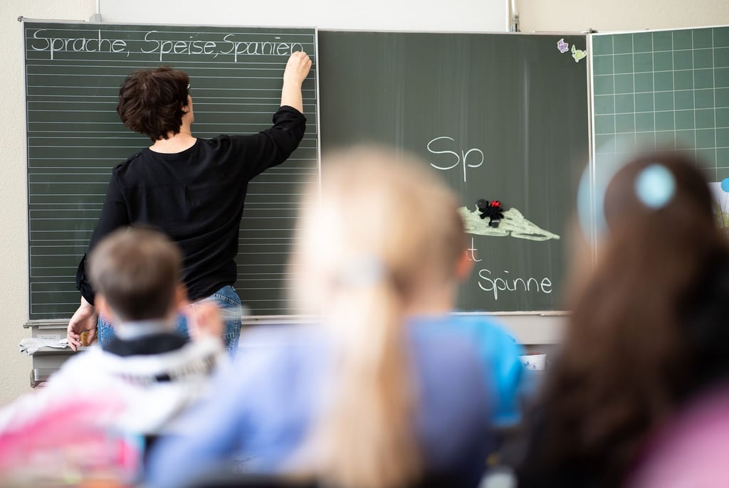Eine Lehrerin schreibt etwas an die Tafel.