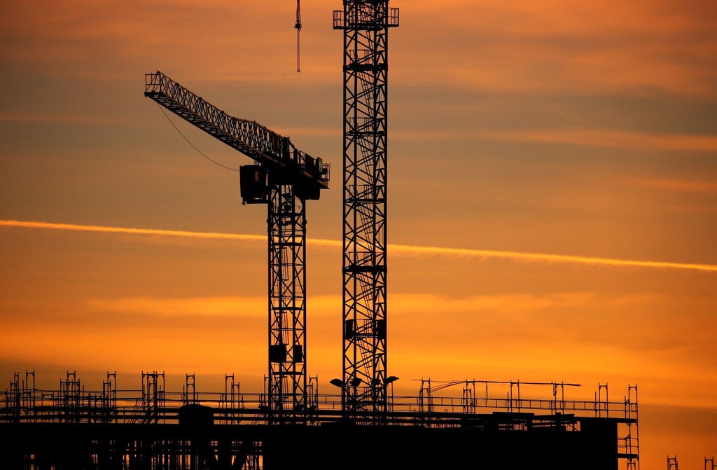 Baukräne einer Großbaustelle bei Sonnenaufgang. Die Stimmung in der Wirtschaft hat sich im Juli überraschend eingetrübt.