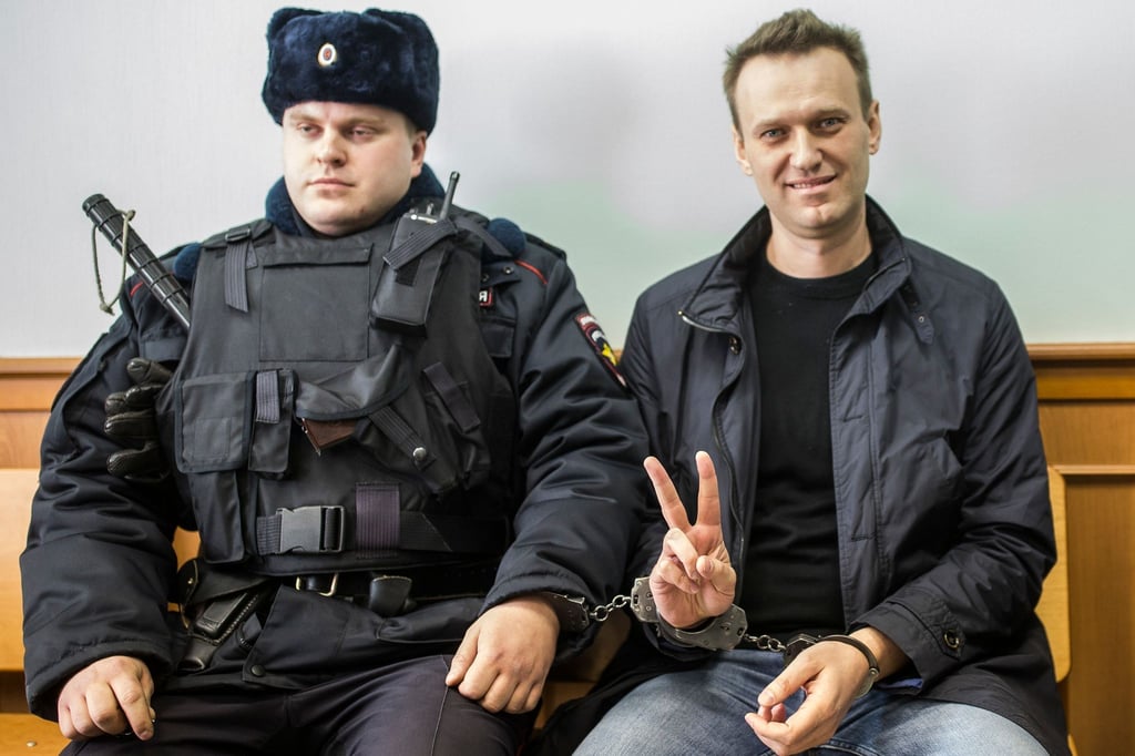 Kremlgegner Alexej Nawalny (r) zeigt ein Victory-Zeichen, während er neben einem Sicherheitsbeamten im Gericht sitzt.
