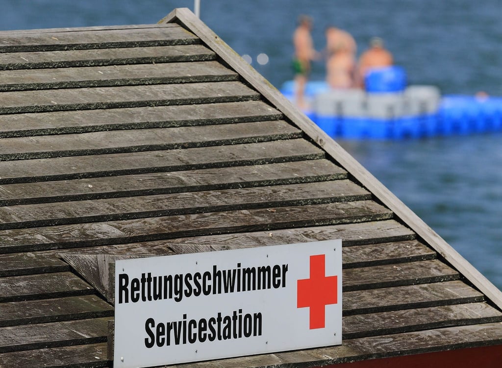 Badende sind auf einem Schwimmponton nahe einer Servicestation der Rettungsschwimmer zu sehen.