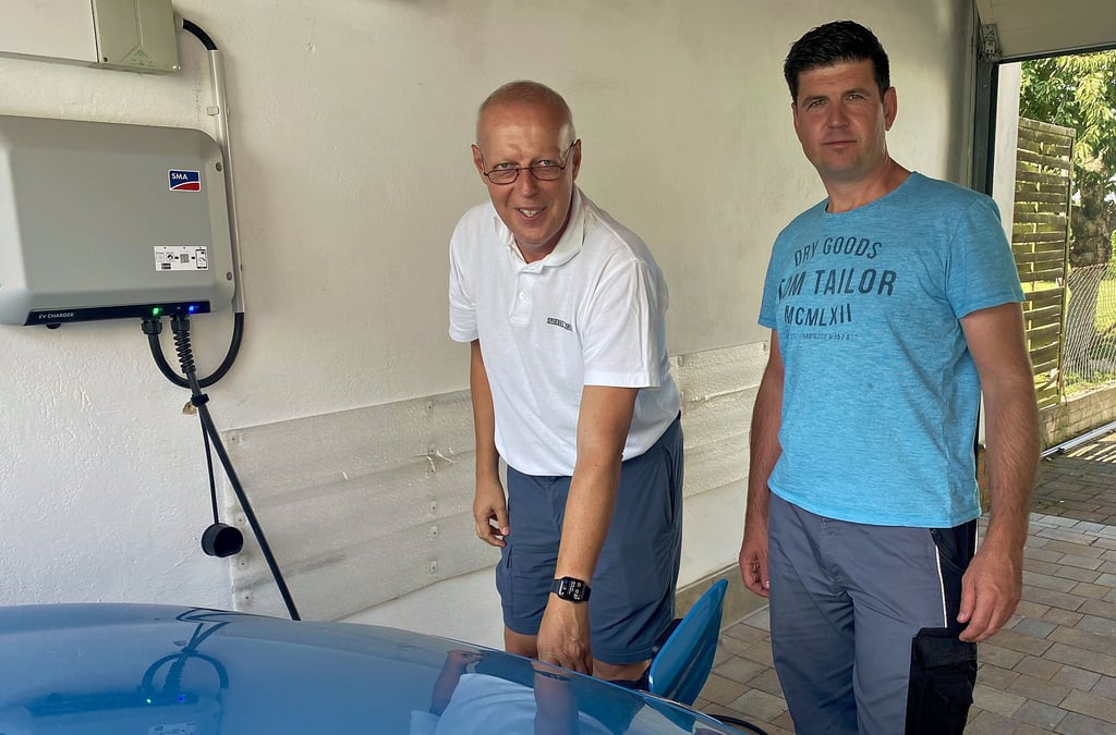 Christian Scholz (li.) und sein Meister Andy Bergholz an einer Ladestation für das firmeneigene E-Auto.