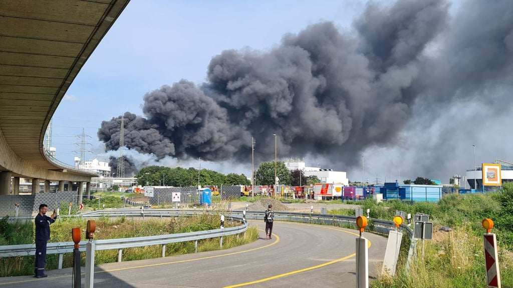 Eine dunkle Rauchwolke steigt über dem Chemiepark auf. Einsatzkräfte der Werkfeuerwehr sind im Einsatz.