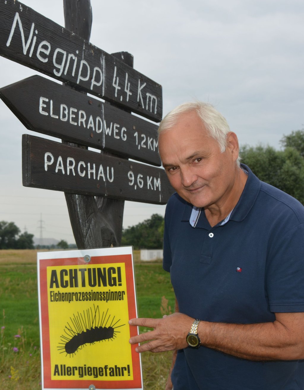 Wieland Günther zeigt auf ein Warnschild, das am Radweg des Schlafdeiches bei Schartau angebracht wurde.