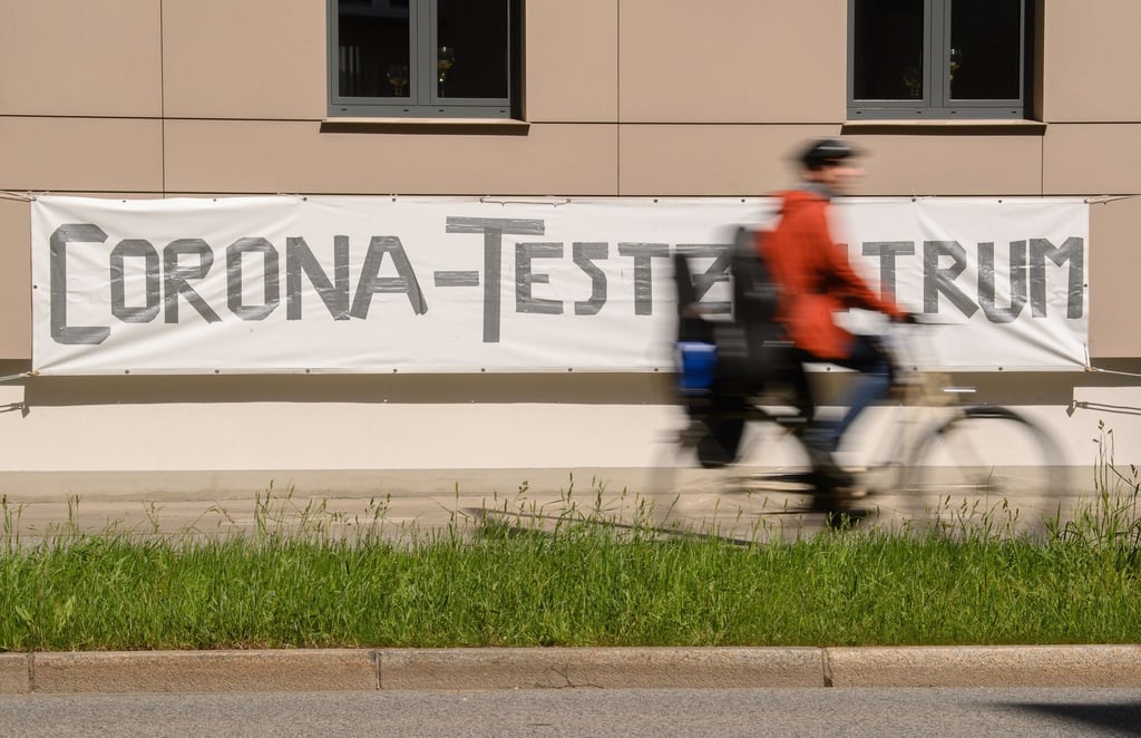 Ein Radfahrer fährt an einem Banner mit der Aufschrift "Corona-Testzentrum" vorbei.