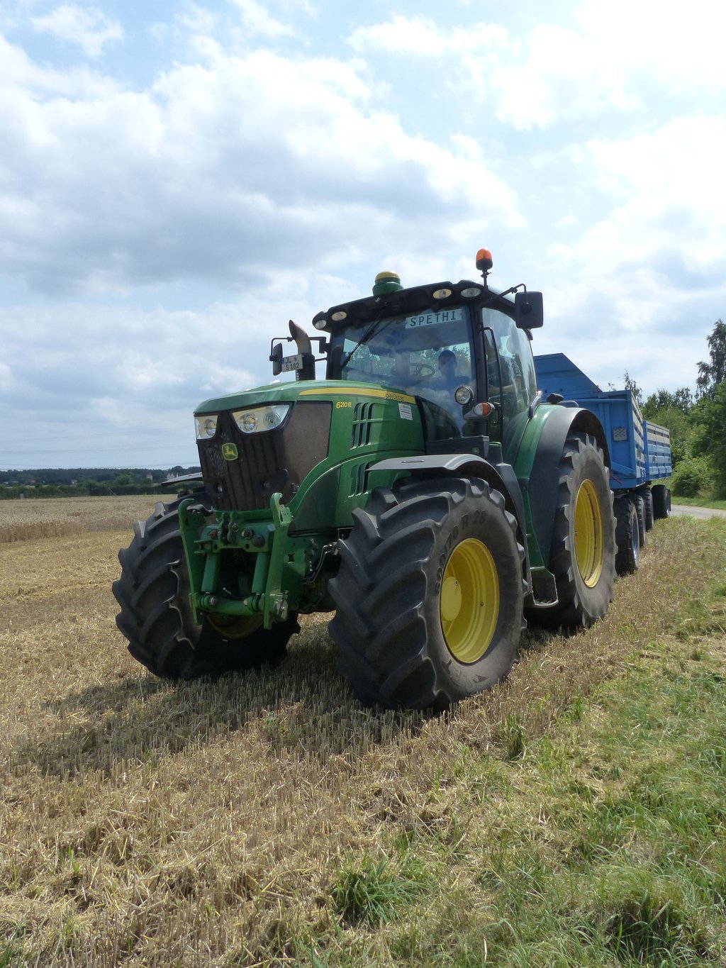 Am Rand des Feldes steht schon ein Traktor bereit, um den geernteten Weizen abzutransportieren.