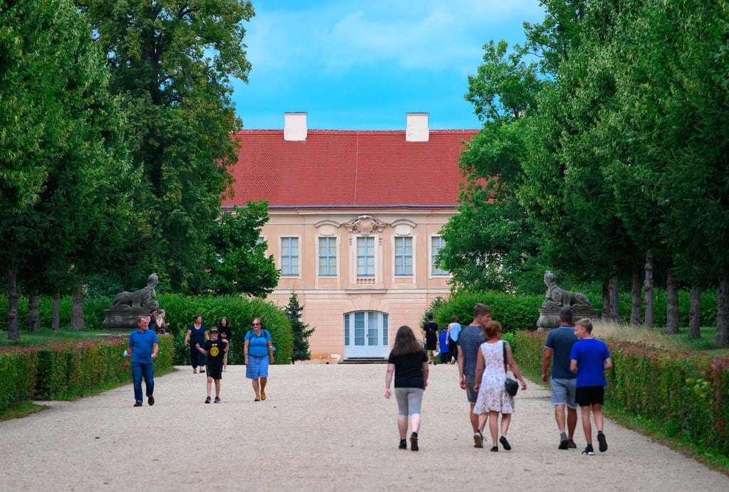 Passanten gehen über einen Parkweg in der Nähe von Schloss Rheinsberg.